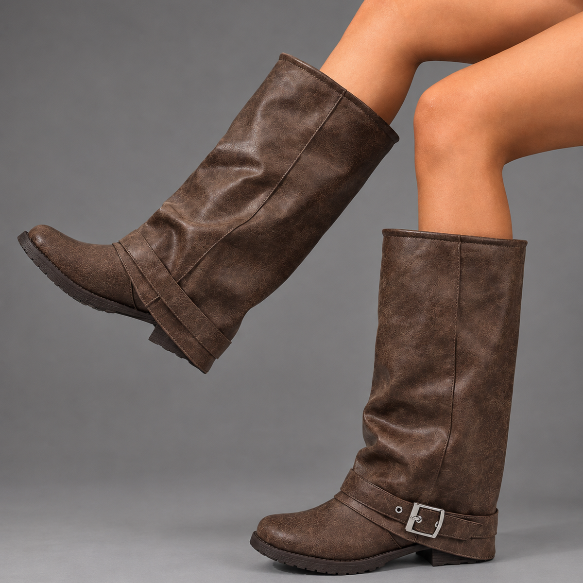 Women’s black slouch knee-high boots with a smooth faux leather upper, round toe, buckle strap detail, low block heel, and chunky lug sole.