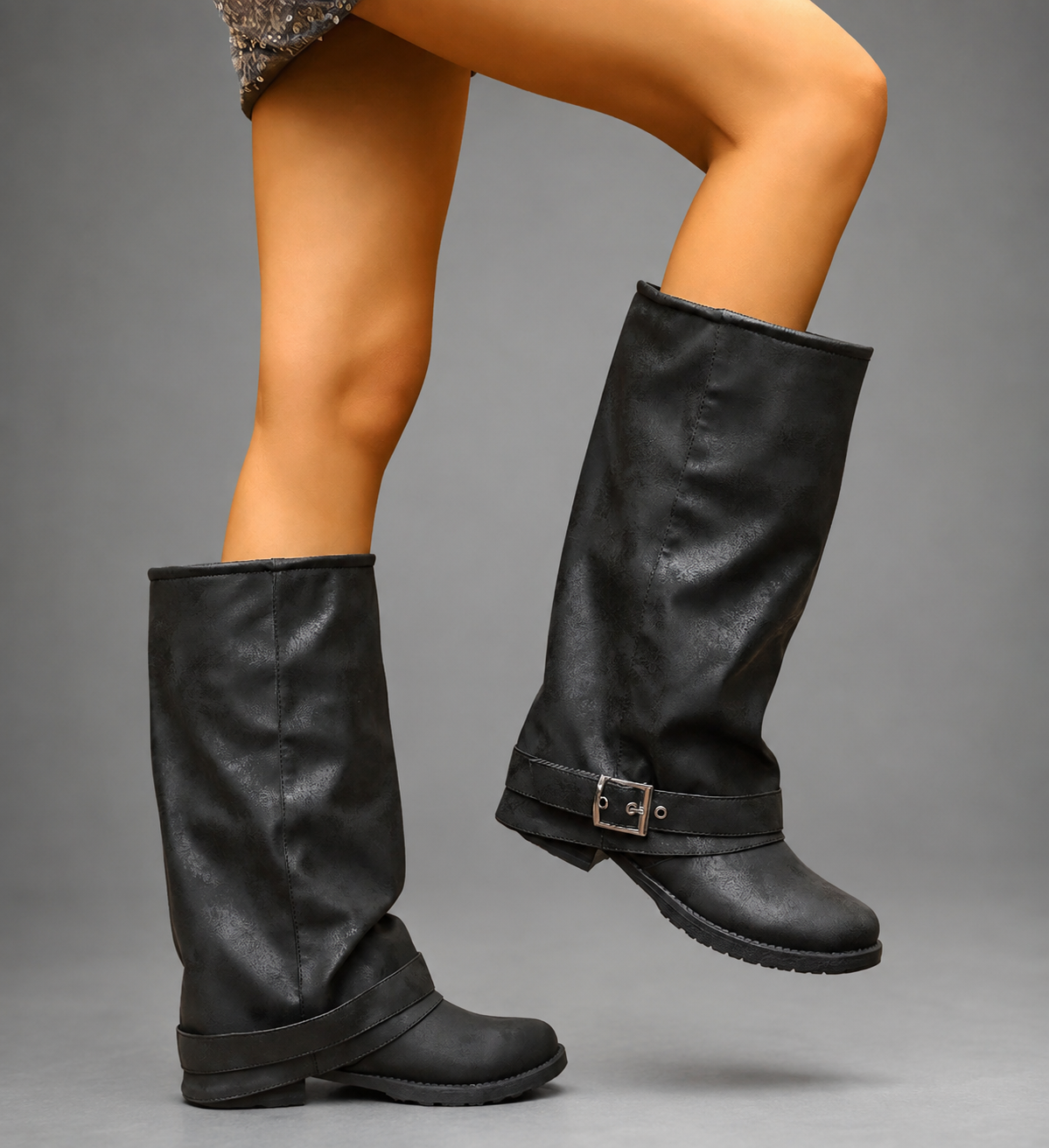 Women’s black slouch knee-high boots with a smooth faux leather upper, round toe, buckle strap detail, low block heel, and chunky lug sole.