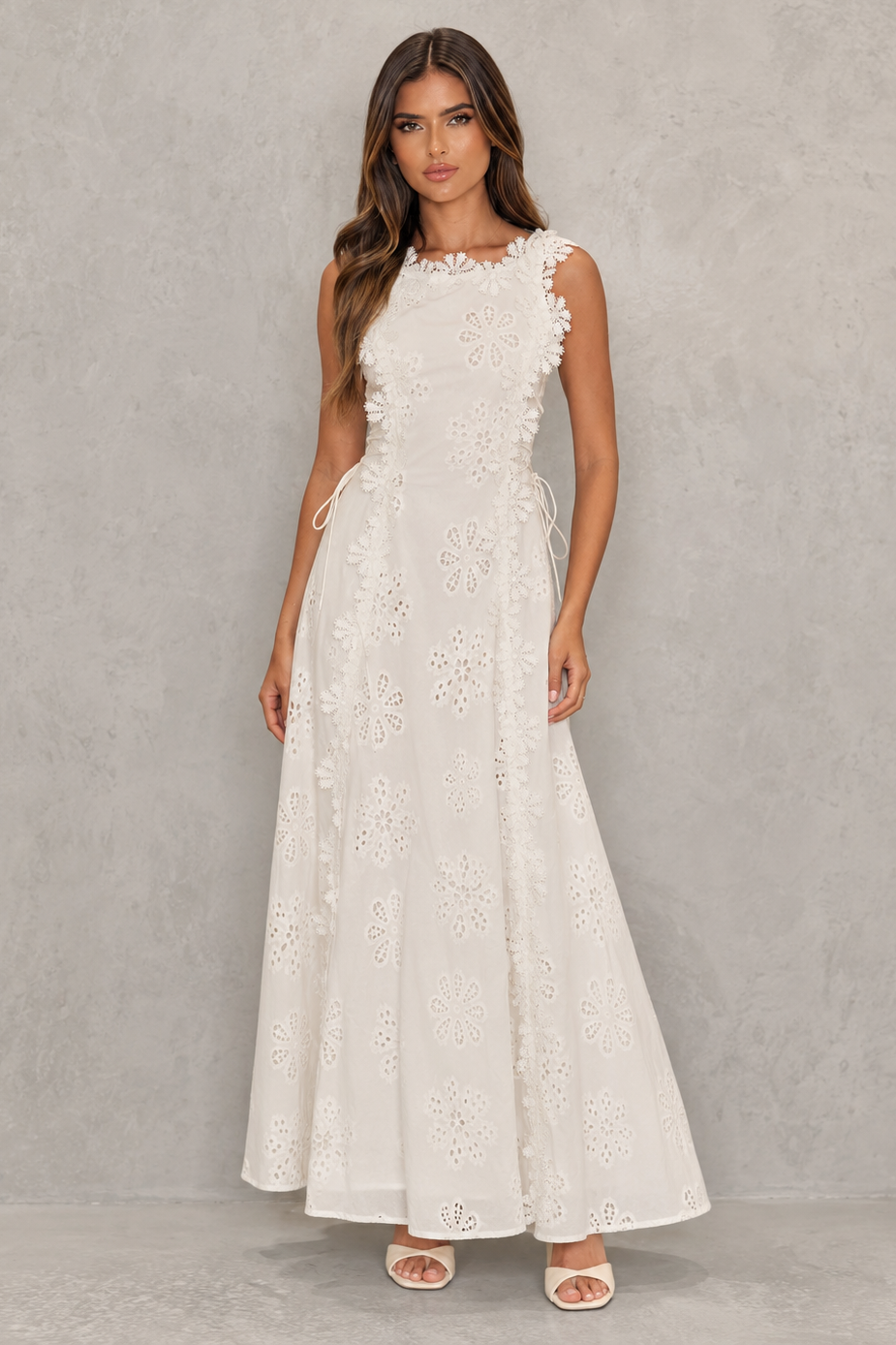 Womenโs embroidered cotton maxi dress with floral detailing, a fitted bodice, lace accents, lace-up detail, and a flowing full-length skirt.