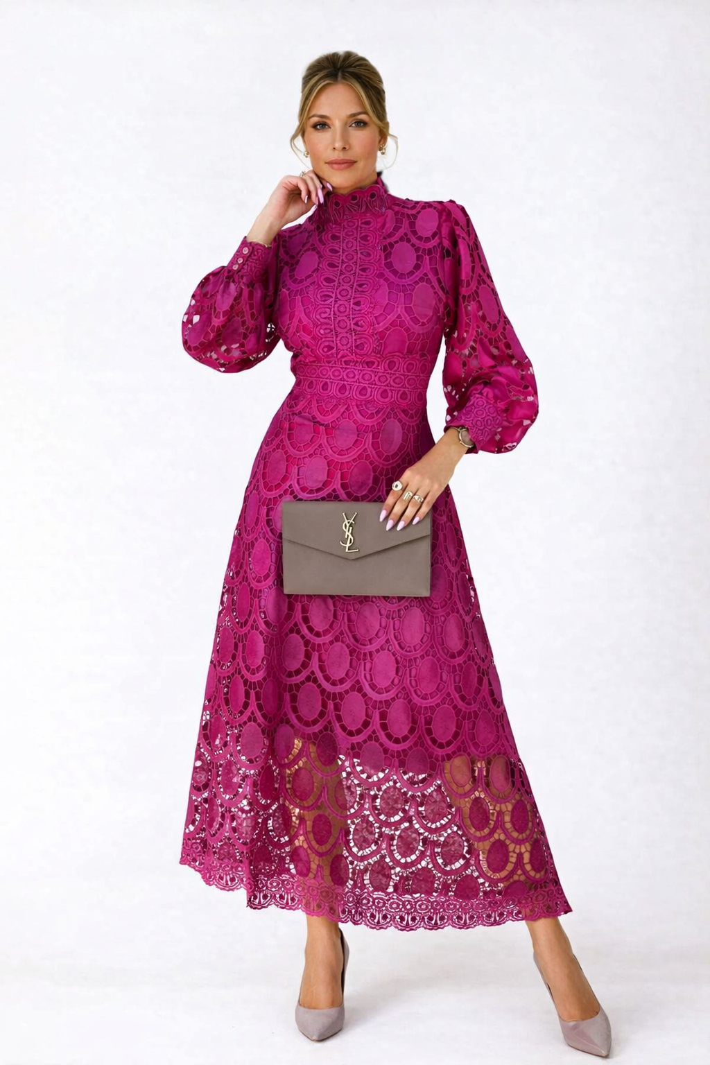 Woman wearing a pink lace dress holding a gray clutch against a white background