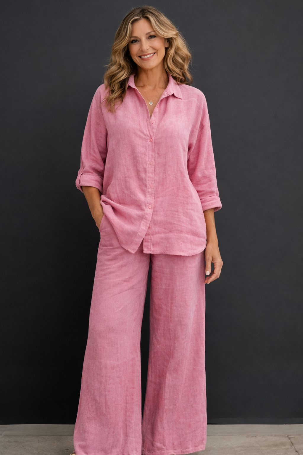 Woman wearing a pink linen set against a black background