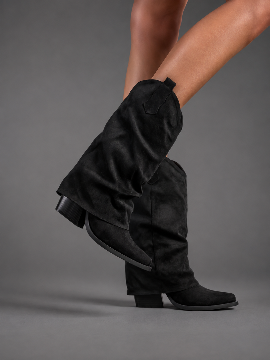 Women’s pointed toe Western knee-high boots with a relaxed slouchy shaft, low chunky heel, decorative pull tabs, and cowboy-inspired silhouette.