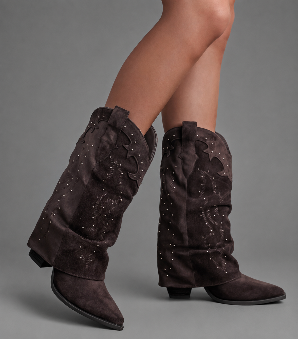 Women’s pointed toe Western knee-high boots with a relaxed slouchy shaft, low chunky heel, decorative pull tabs, and cowboy-inspired silhouette.
