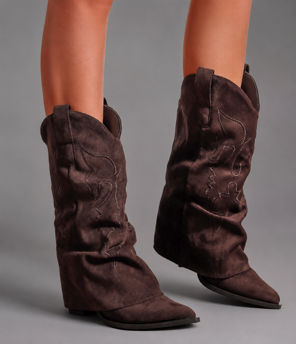 Women’s pointed toe Western knee-high boots with a relaxed slouchy shaft, low chunky heel, decorative pull tabs, and cowboy-inspired silhouette.