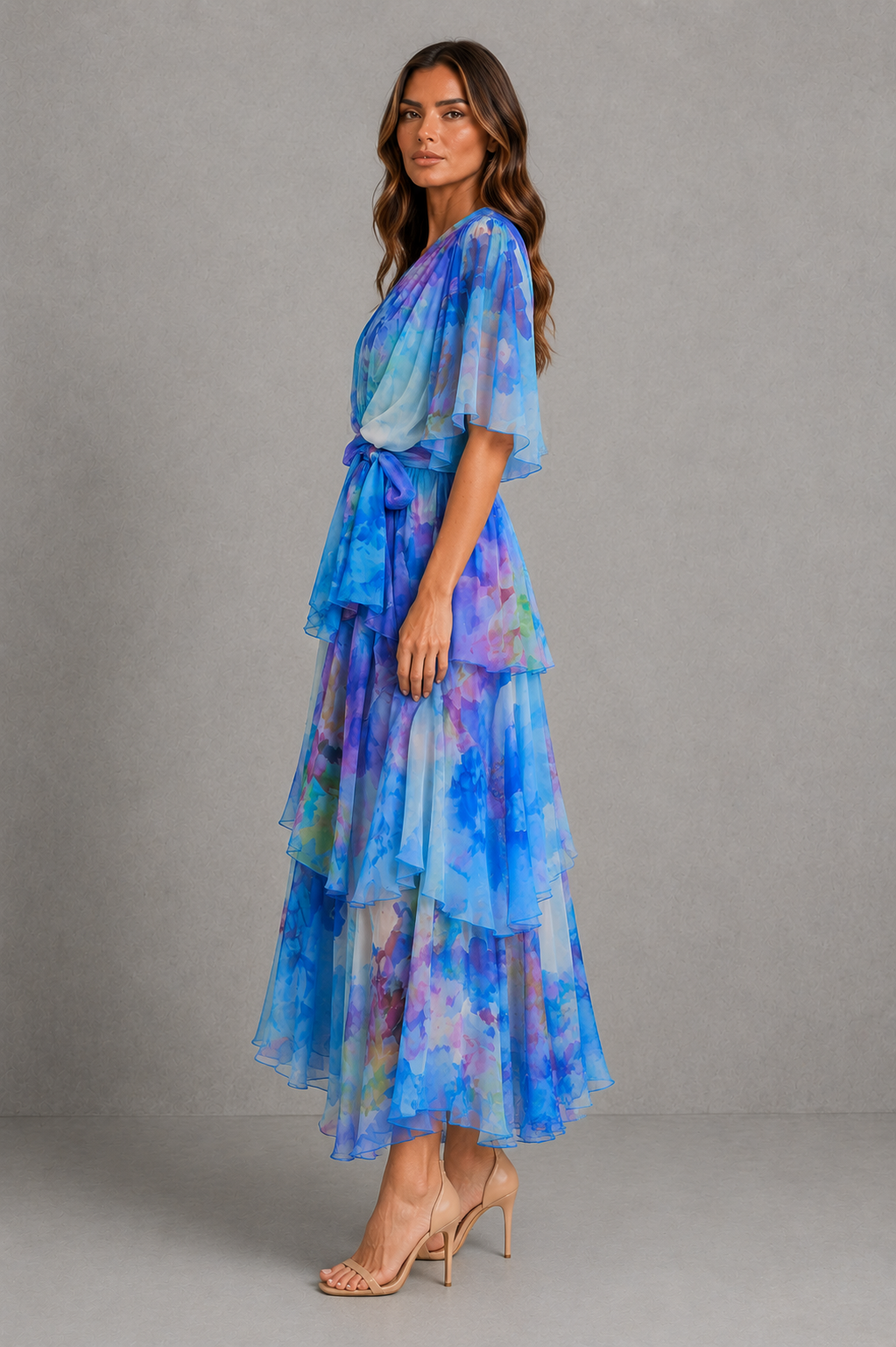 Womenโs watercolour chiffon maxi dress with wrap V-neckline, flutter sleeves, tie waist and tiered skirt in soft pastel floral tones.