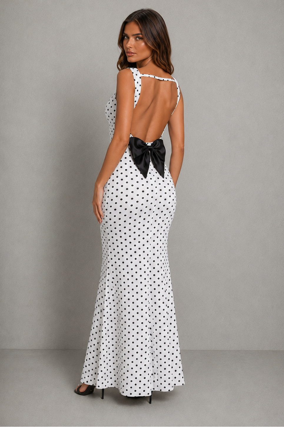 Women’s backless polka dot maxi dress with statement bow detail, sleeveless design, and flattering body-skimming silhouette.