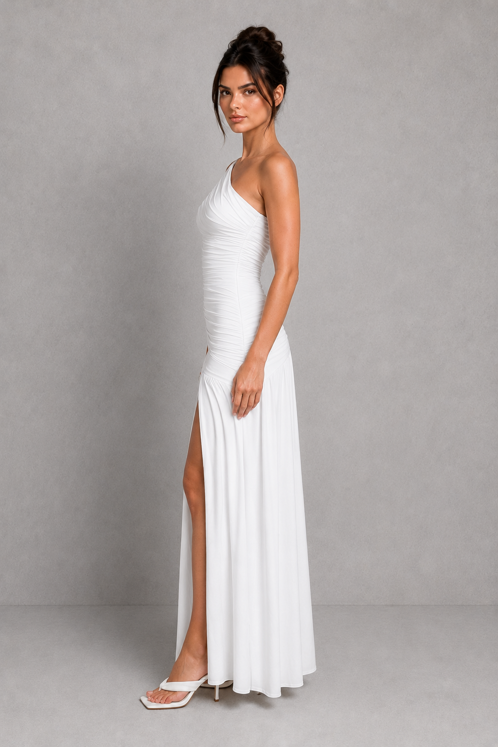 Woman wearing a one-shoulder maxi dress with gathered waist detailing, thigh-high split, and flowing skirt in premium slinky jersey for evening and formal occasions.