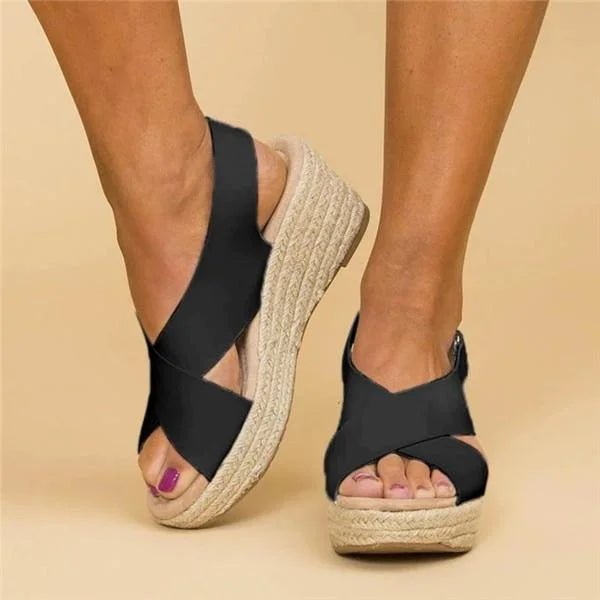 Black wedge sandals with espadrille sole on a beige background