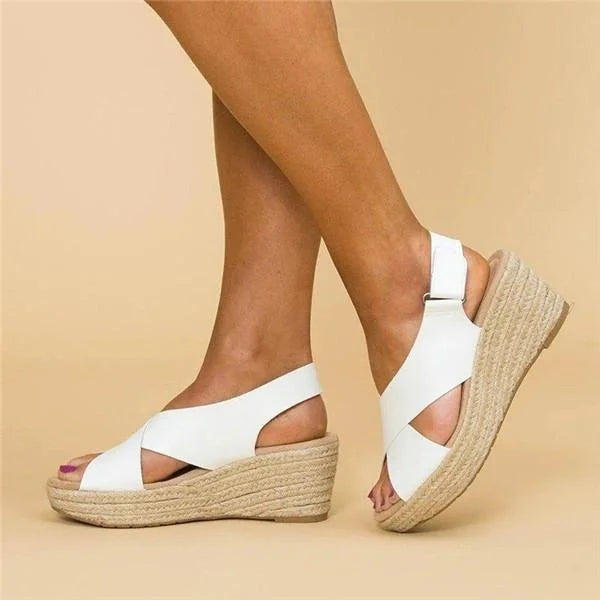 White sandals with woven soles worn by a person on a beige background