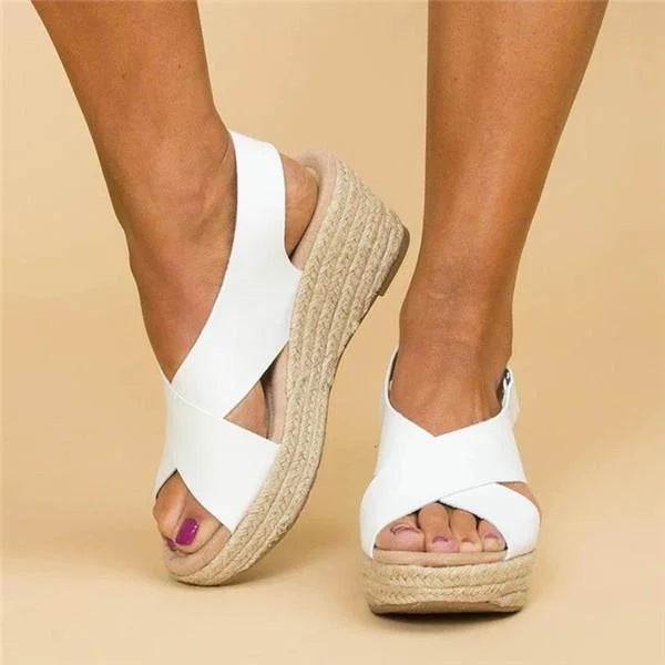 White sandals with espadrille sole worn by a person on a beige background
