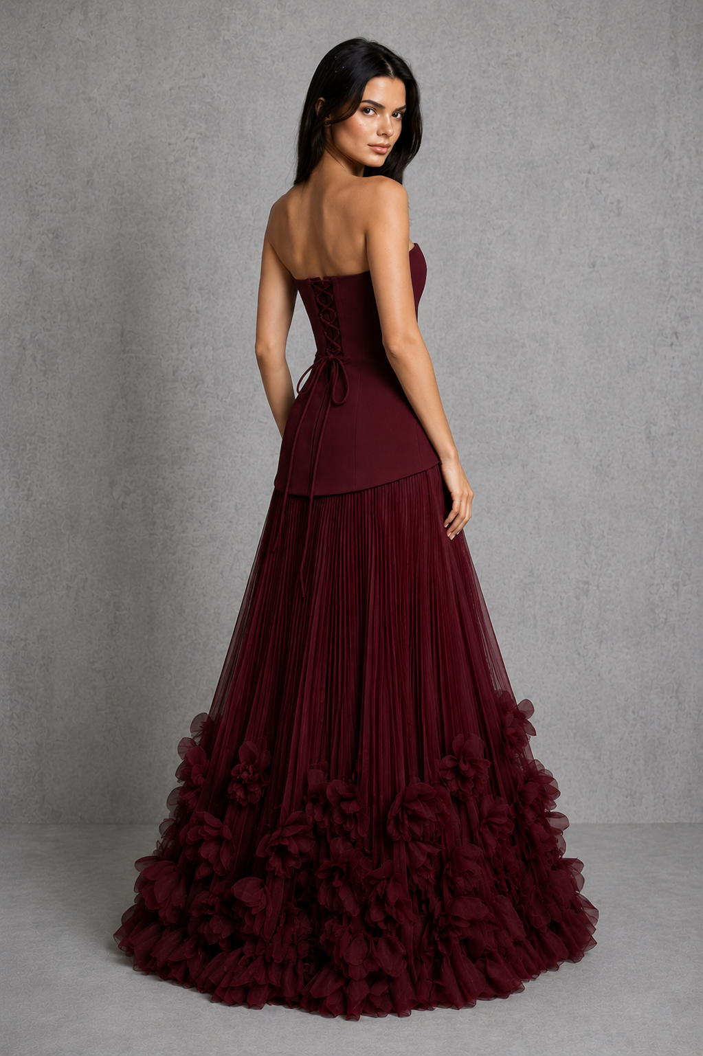 Women’s strapless corset gown with lace-up back, fitted bodice, full pleated skirt, and handcrafted floral appliqué detailing along the hem.