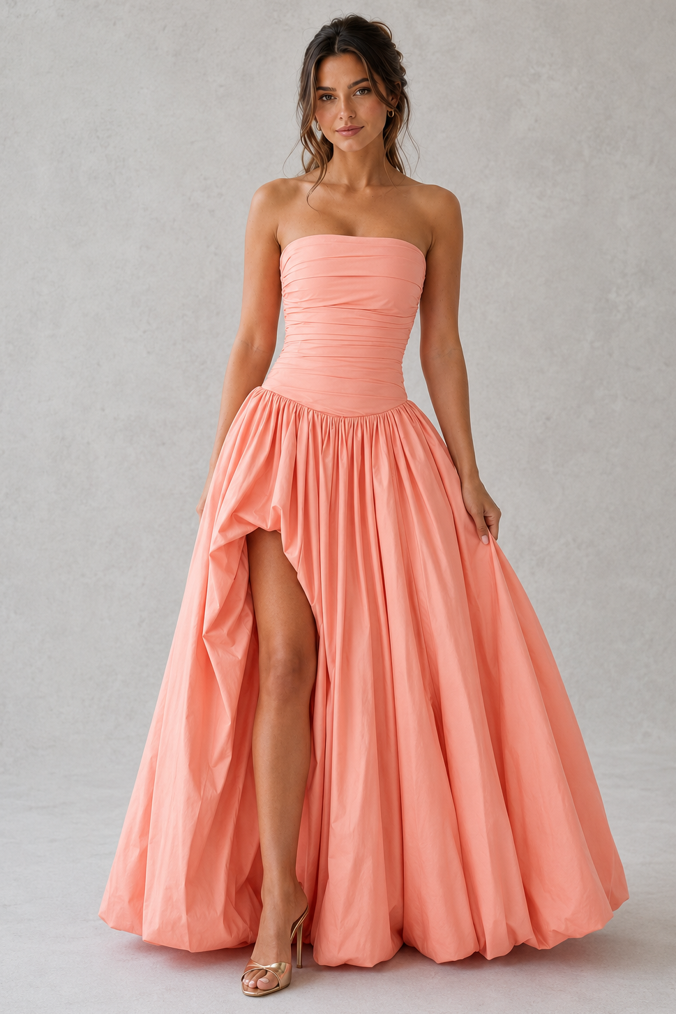 Women's strapless maxi dress with a ruched fitted bodice, dropped waist, lace-up back, dramatic puffball skirt, and thigh-high split, designed for elegant evening events and formal occasions.