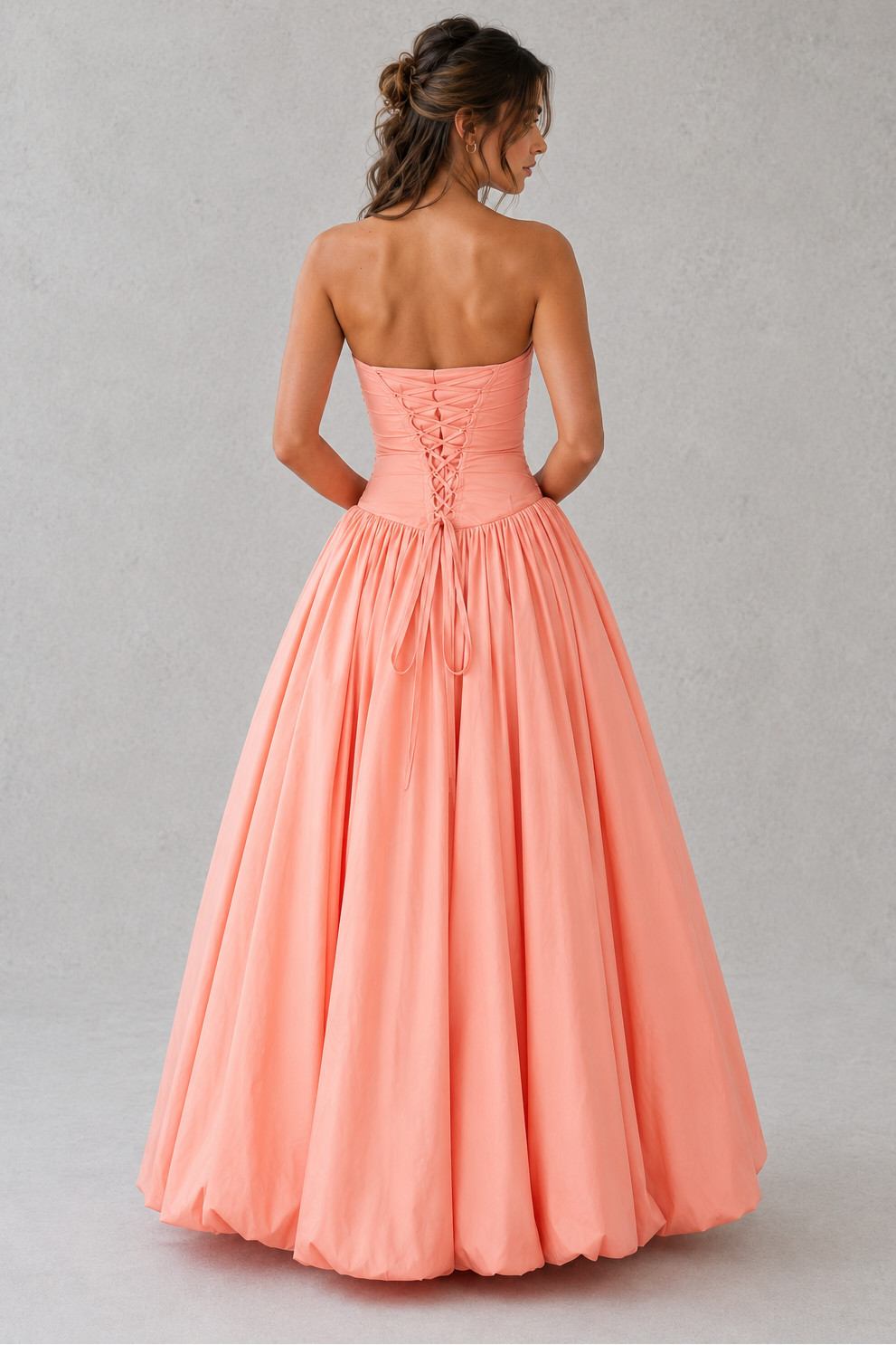 Women's strapless maxi dress with a ruched fitted bodice, dropped waist, lace-up back, dramatic puffball skirt, and thigh-high split, designed for elegant evening events and formal occasions.
