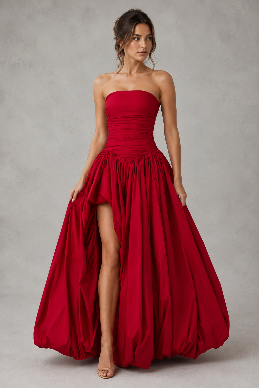 Women's strapless maxi dress with a ruched fitted bodice, dropped waist, lace-up back, dramatic puffball skirt, and thigh-high split, designed for elegant evening events and formal occasions.