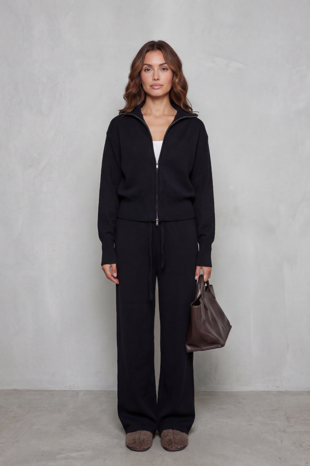 Black knit lounge set styled with a structured handbag and sneakers