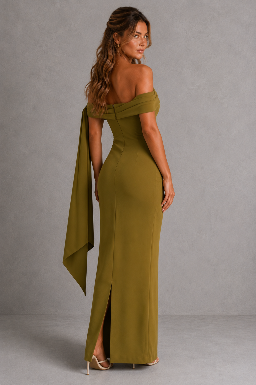 Woman wearing a premium bardot maxi dress with an asymmetric pleated neckline, draped knot shoulder tie, fitted bodice, asymmetric pleated waist, column skirt, and centre back split in structured crepe fabric.