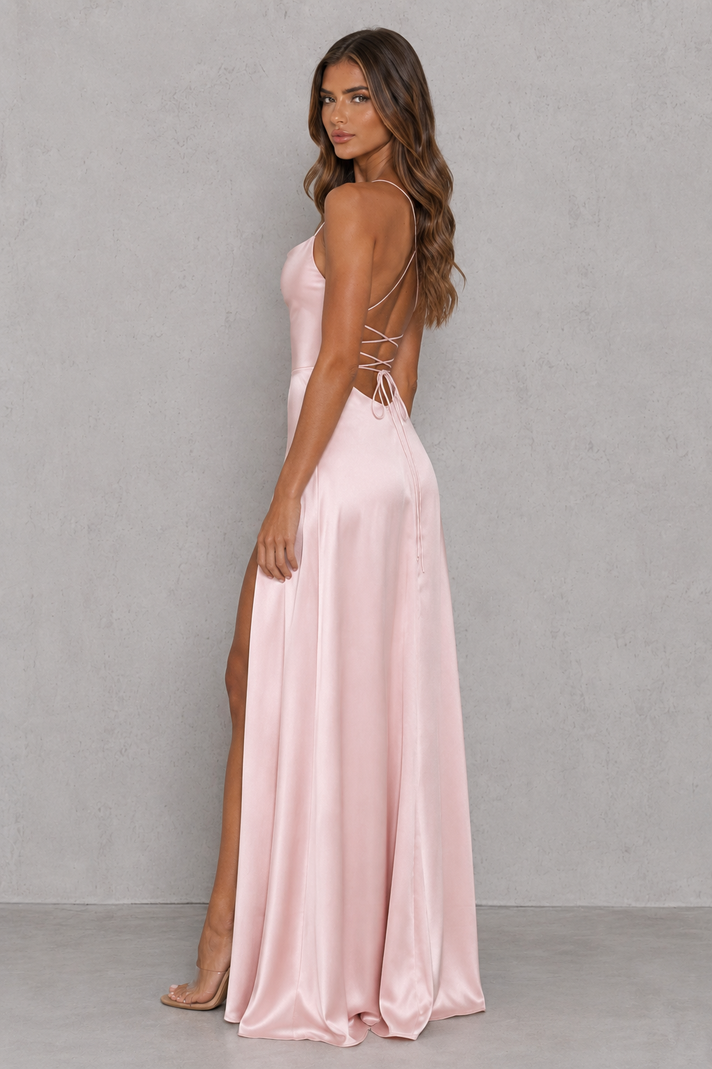 Women's blush bias-cut satin maxi dress with a low neckline, adjustable shoulder straps, open criss-cross back, thigh-high side split, and elegant figure-skimming silhouette for evening and formal occasions.