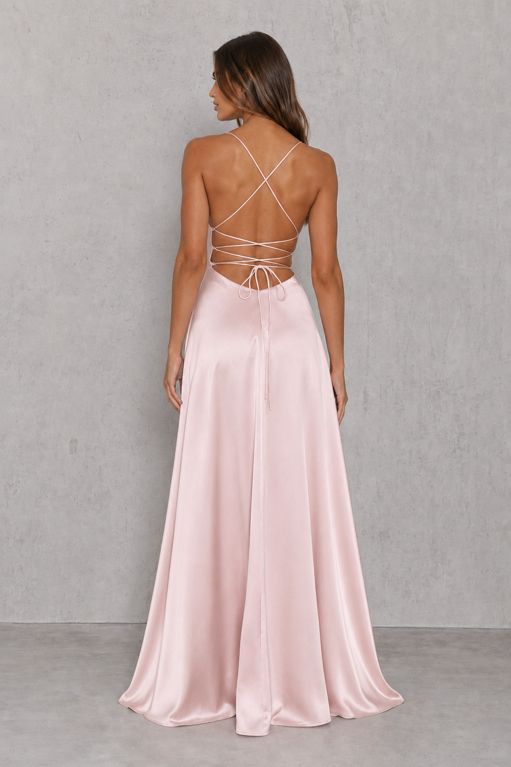 Women's blush bias-cut satin maxi dress with a low neckline, adjustable shoulder straps, open criss-cross back, thigh-high side split, and elegant figure-skimming silhouette for evening and formal occasions.