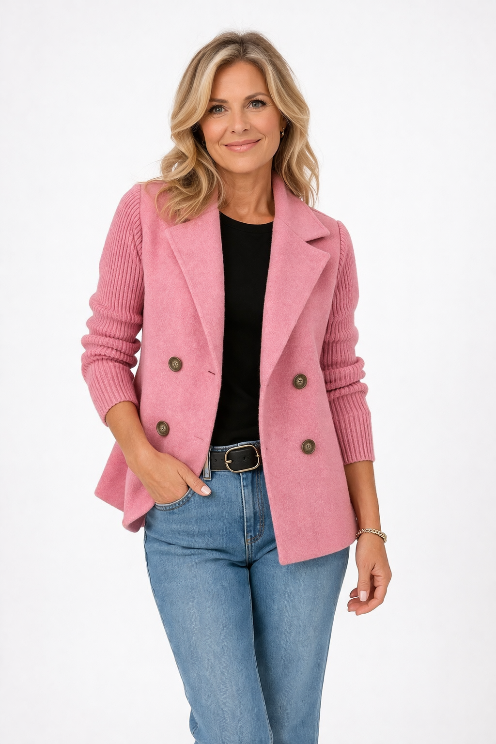 Woman wearing a pink blazer over a black top and blue jeans on a white background