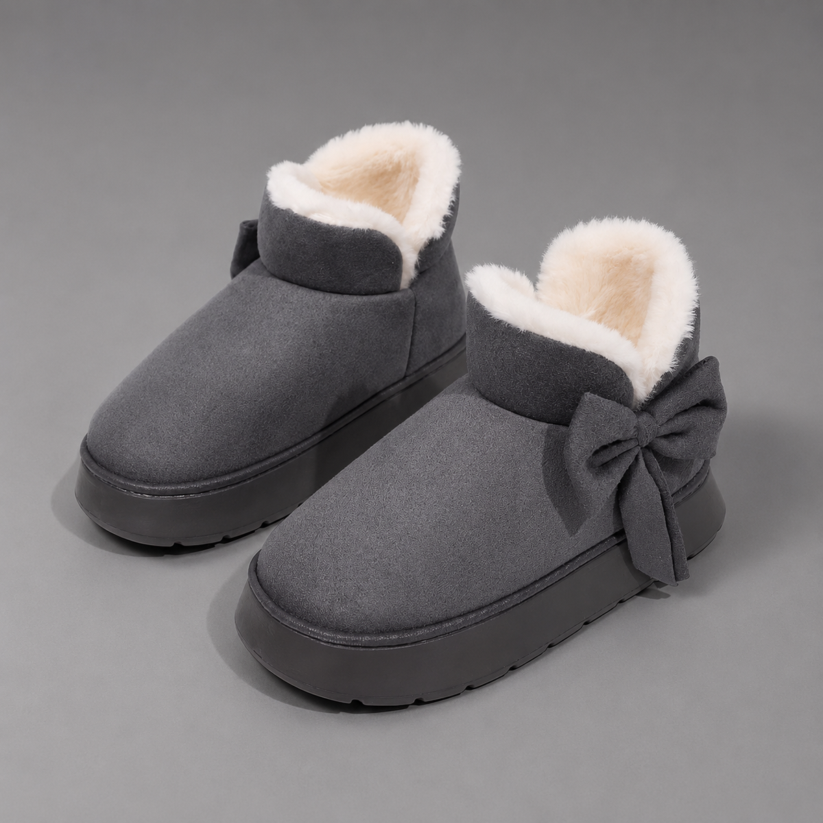 Women’s fleece-lined slipper boots with a soft faux suede upper, plush lining, side bow detail, cushioned platform sole, and slip-on design.