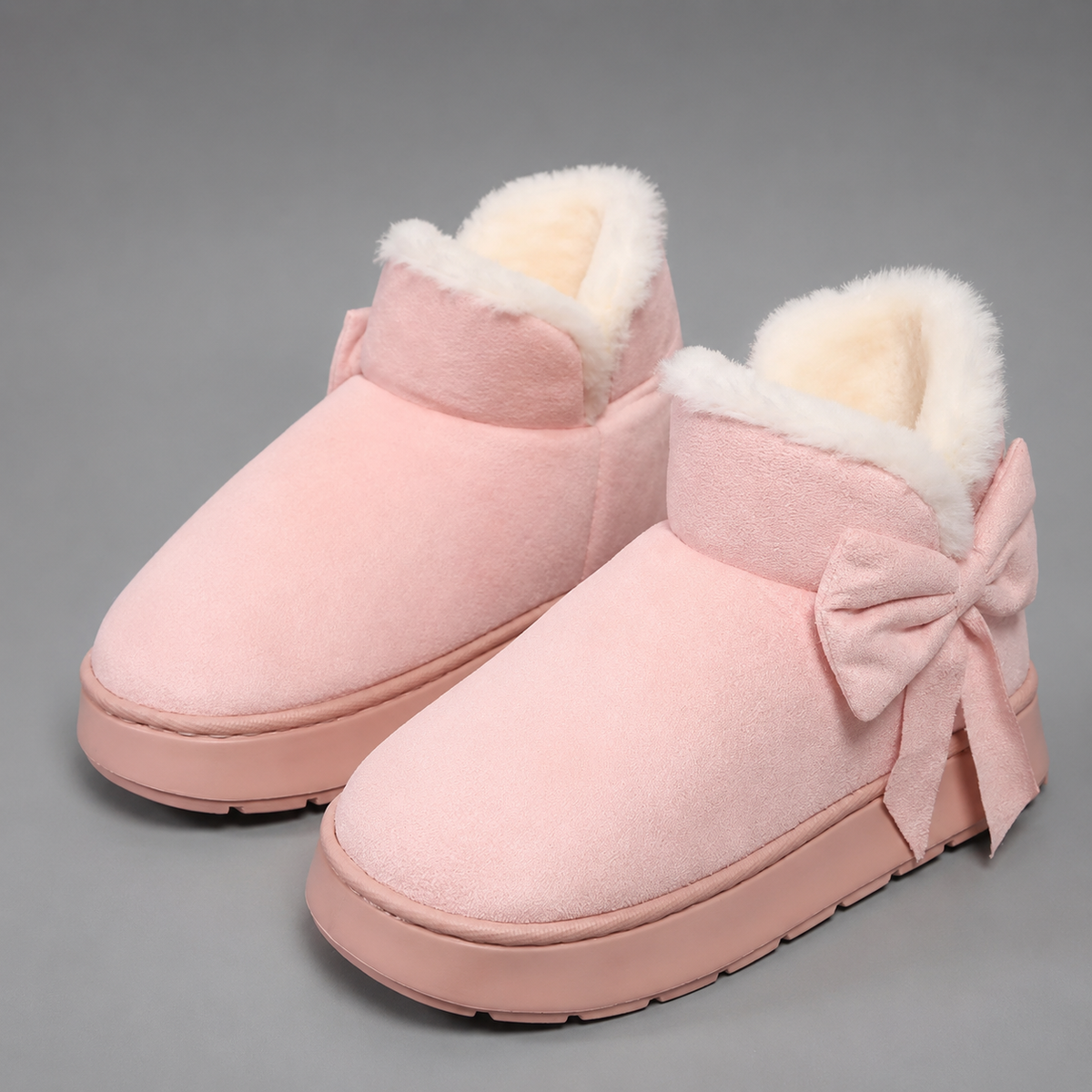 Women’s fleece-lined slipper boots with a soft faux suede upper, plush lining, side bow detail, cushioned platform sole, and slip-on design.