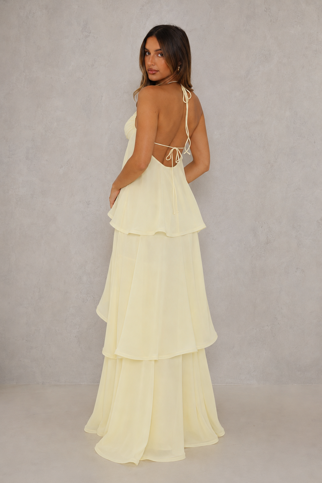 Women’s halter tiered maxi dress with V-neckline, self-tie straps, low open back and flowing layered floor-length skirt.