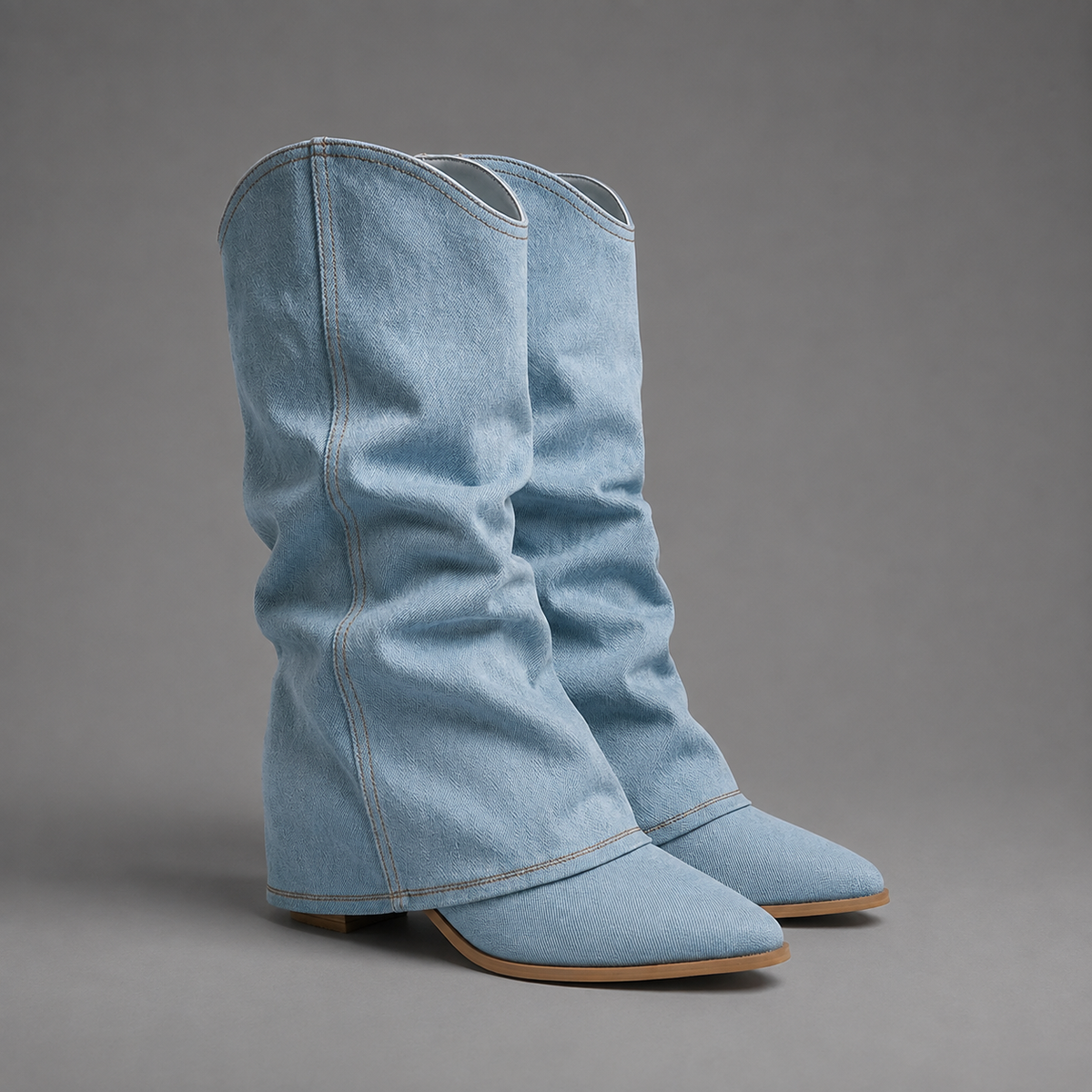 Women’s light blue denim knee-high boots with a ruched shaft, sleek pointed toe, square block heel, and statement denim finish.