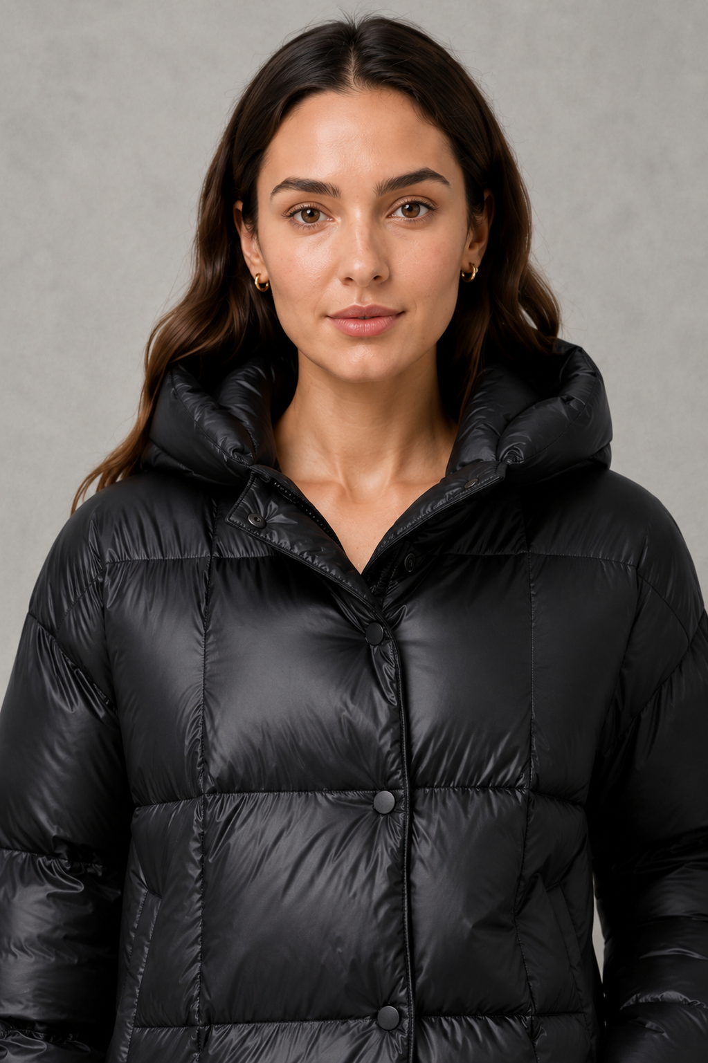 Women’s oversized hooded puffer jacket with generous padding, a large protective hood, high collar and wide long sleeves for cozy cold-weather coverage.