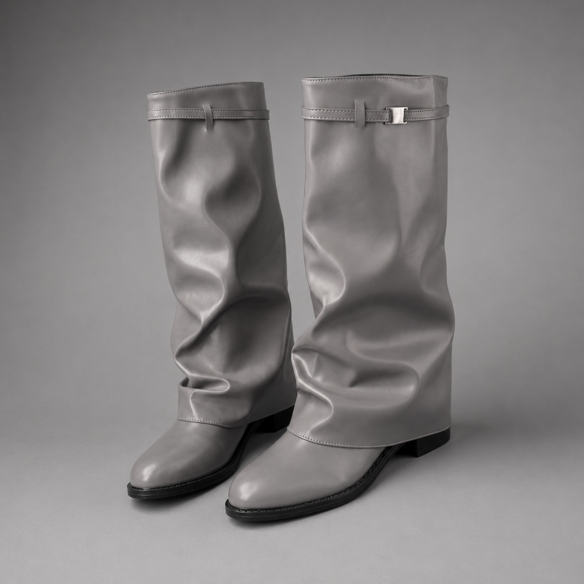 Women’s pointed toe slouch knee-high boots with a relaxed shaft, low block heel, pull-on design, and polished metal cuff detail.