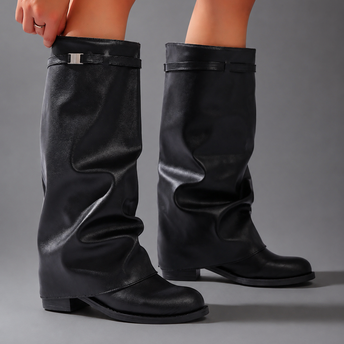 Women’s pointed toe slouch knee-high boots with a relaxed shaft, low block heel, pull-on design, and polished metal cuff detail.