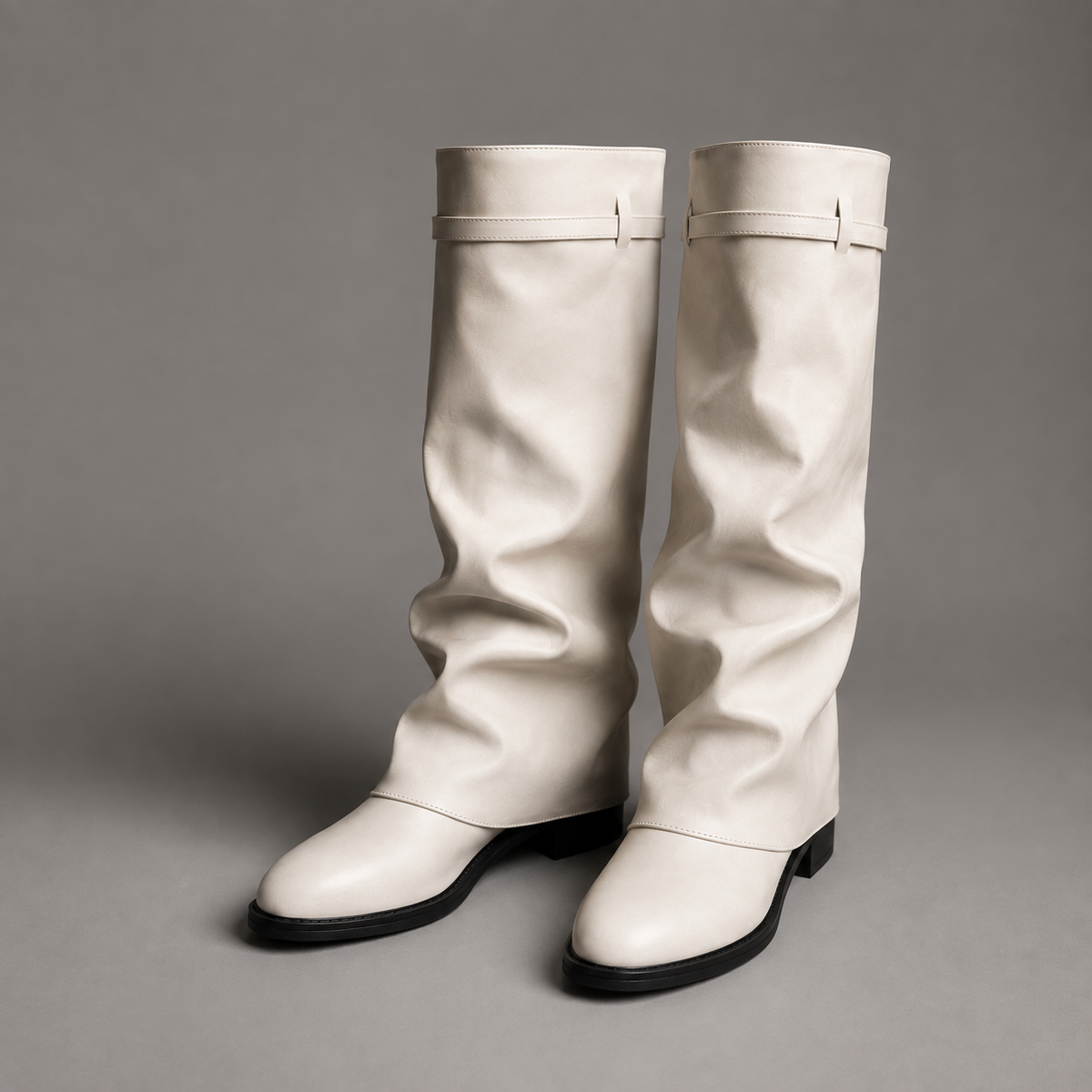 Women’s pointed toe slouch knee-high boots with a relaxed shaft, low block heel, pull-on design, and polished metal cuff detail.