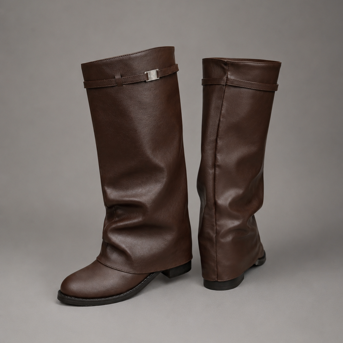 Women’s pointed toe slouch knee-high boots with a relaxed shaft, low block heel, pull-on design, and polished metal cuff detail.