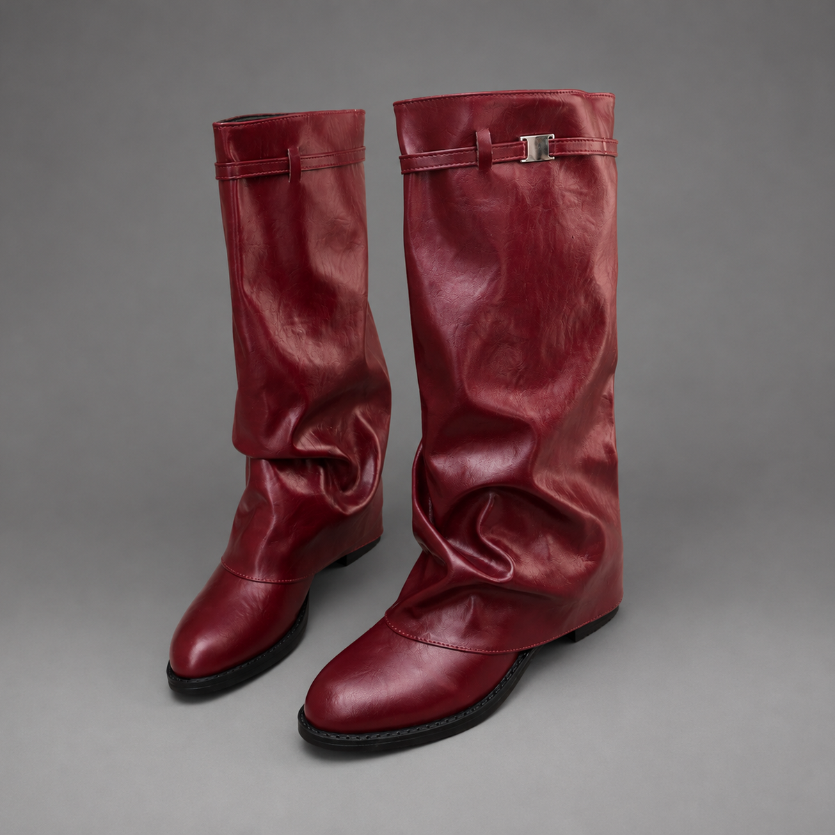Women’s pointed toe slouch knee-high boots with a relaxed shaft, low block heel, pull-on design, and polished metal cuff detail.