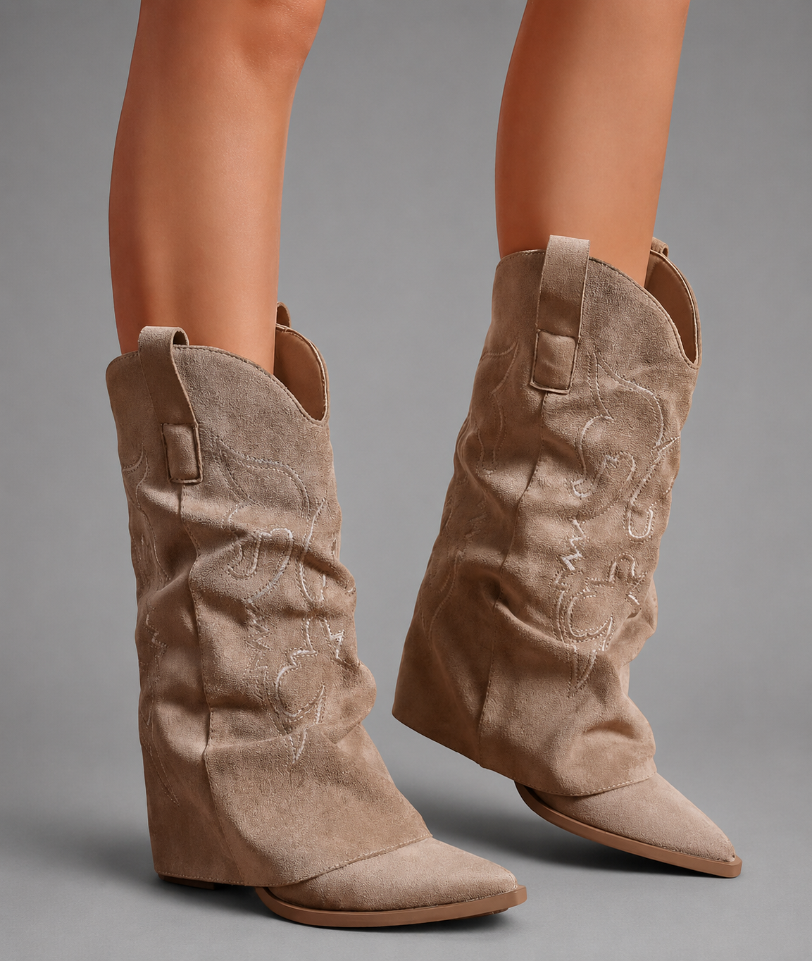 Women’s pointed toe Western knee-high boots with a relaxed slouchy shaft, low chunky heel, decorative pull tabs, and cowboy-inspired silhouette.