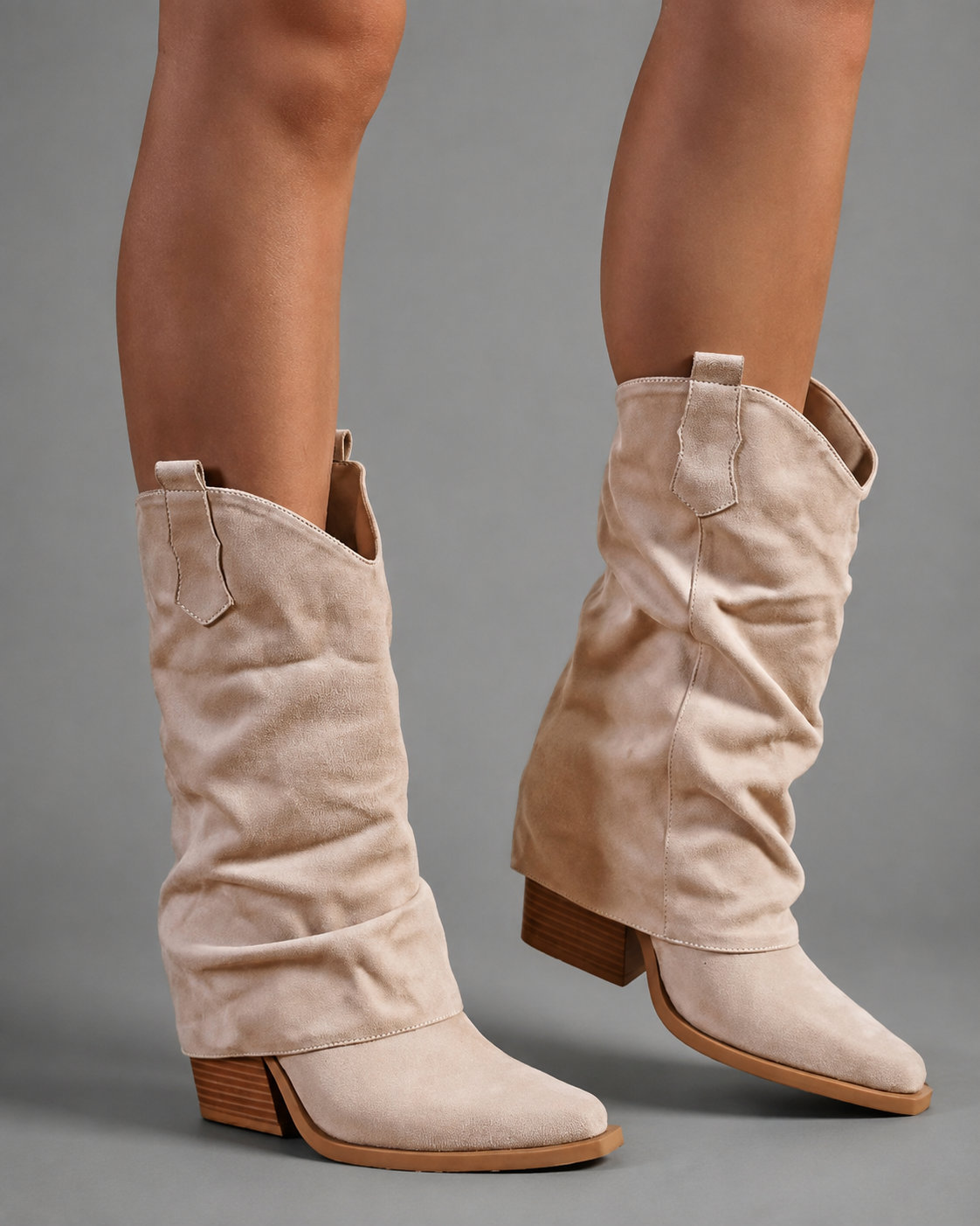 Women’s pointed toe Western knee-high boots with a relaxed slouchy shaft, low chunky heel, decorative pull tabs, and cowboy-inspired silhouette.
