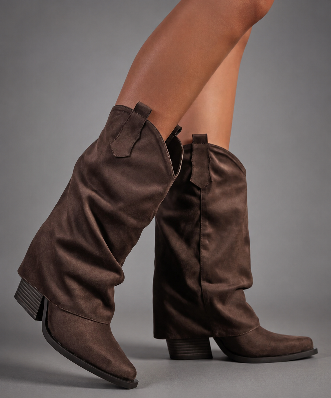 Women’s pointed toe Western knee-high boots with a relaxed slouchy shaft, low chunky heel, decorative pull tabs, and cowboy-inspired silhouette.