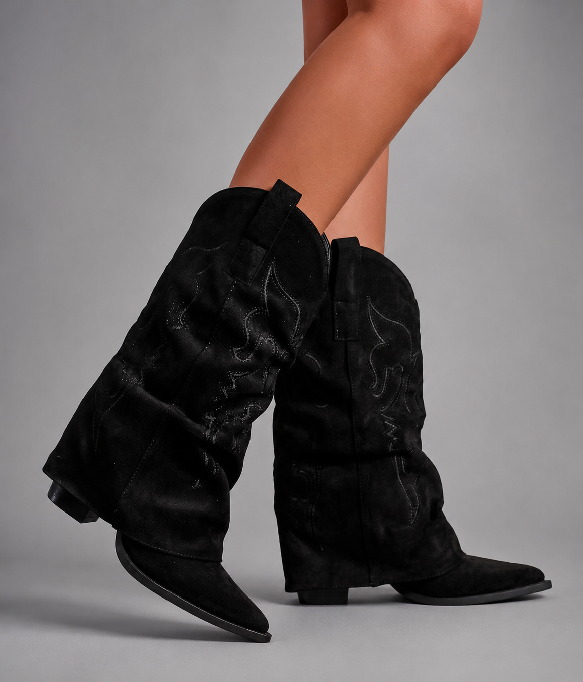 Women’s pointed toe Western knee-high boots with a relaxed slouchy shaft, low chunky heel, decorative pull tabs, and cowboy-inspired silhouette.