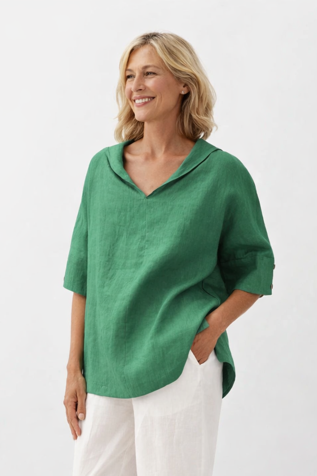 Woman wearing a green top and white pants on a white background