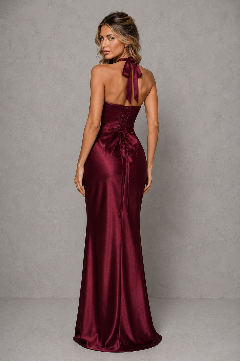 Women’s satin halter maxi dress with plunge neckline, pleated cups, structured corset bodice, lace-up back, and flowing bias-cut skirt.