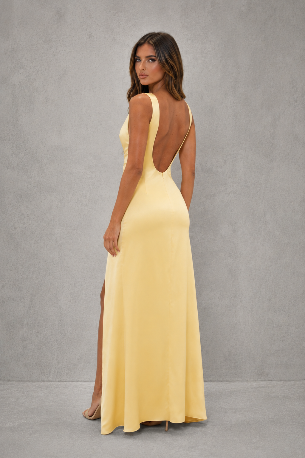 Women's satin maxi dress with a fitted bodice, asymmetrical pleated waist, draped thigh-high split, removable floral corsage, high neckline, and low scoop back for elegant evening and formal occasions.