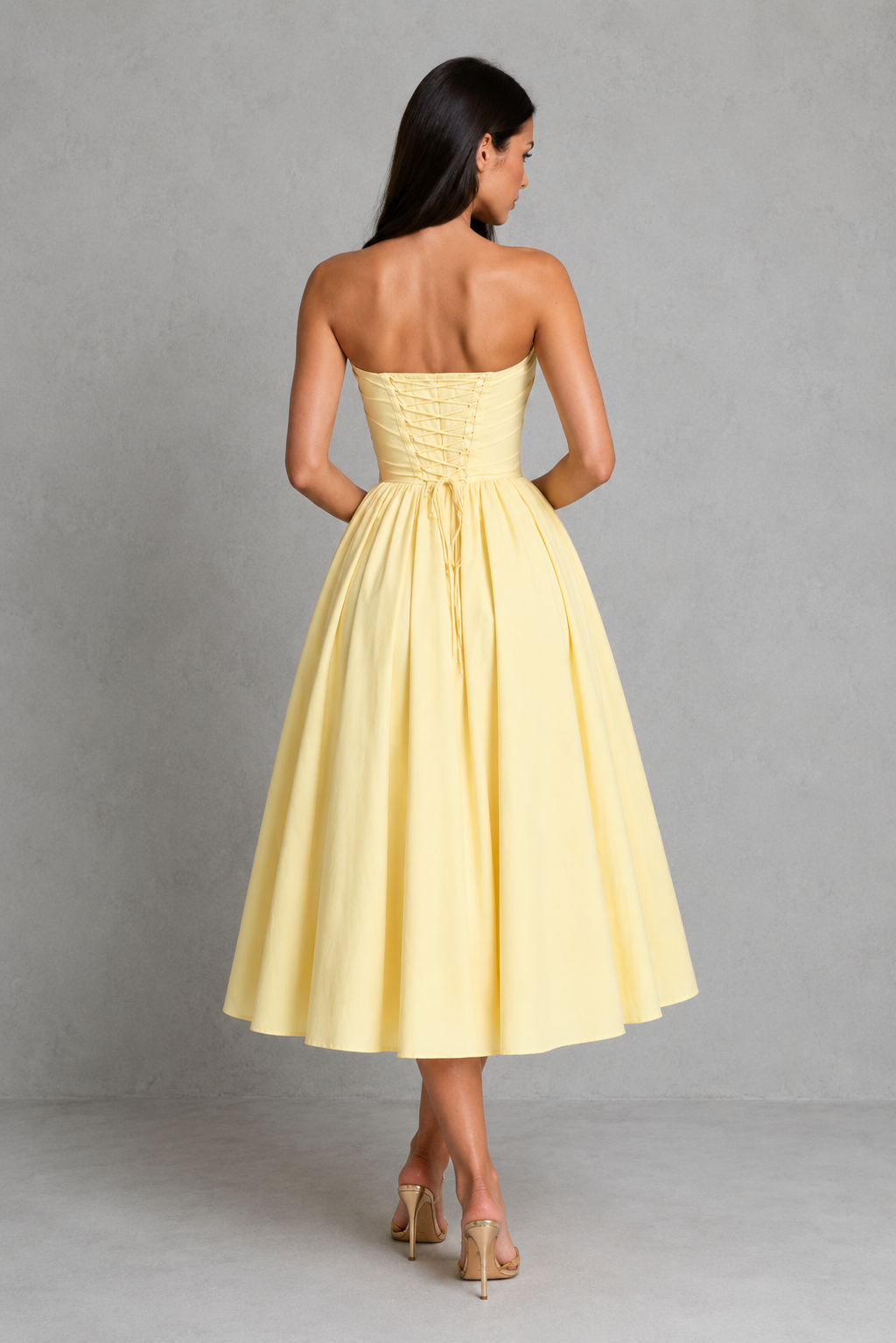 Women's strapless corset midi dress with a sweetheart neckline, pleated cups, bow detail, structured boned bodice, and a full tulle-lined gathered skirt, designed for elegant party and occasion wear.
