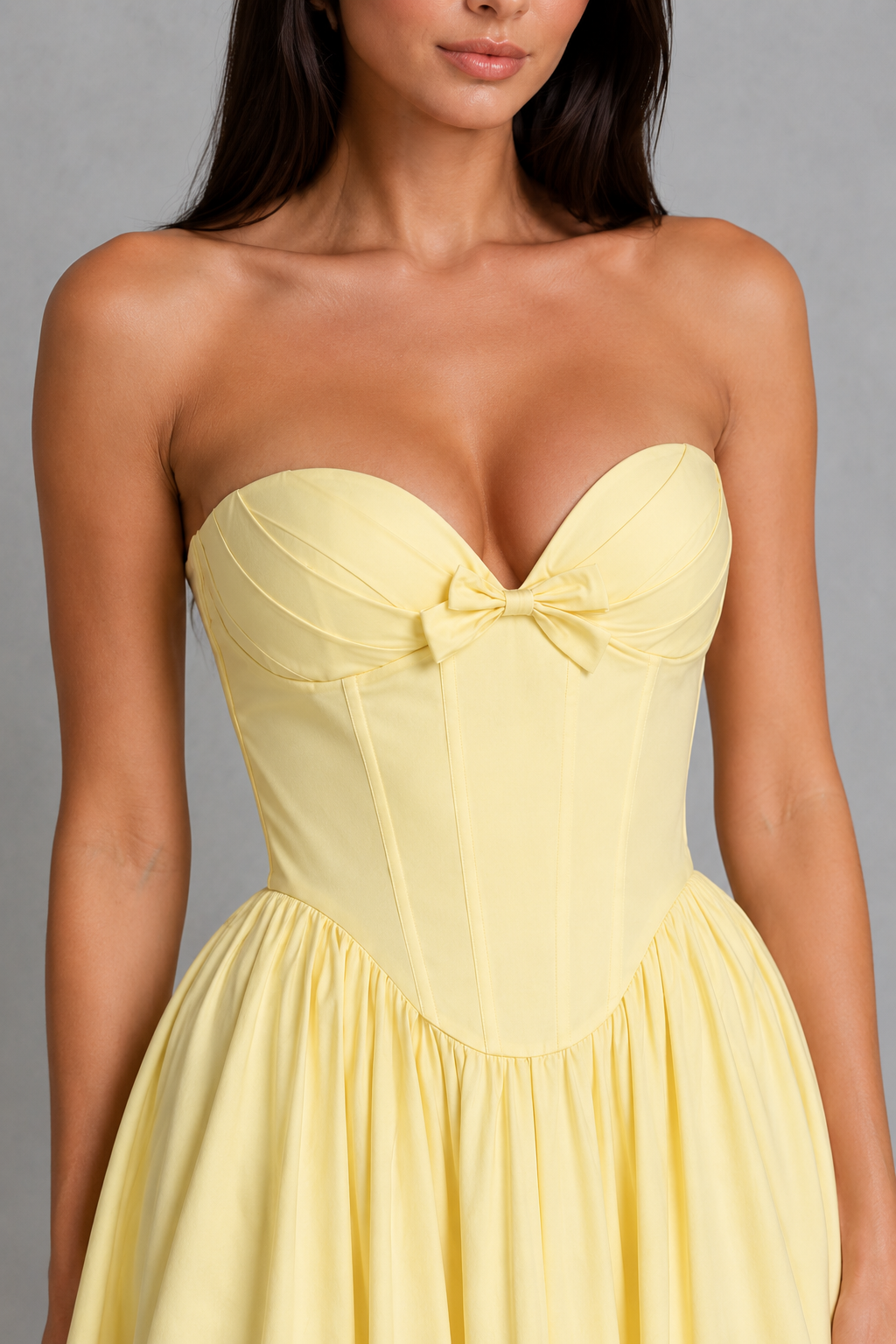 Women's strapless corset midi dress with a sweetheart neckline, pleated cups, bow detail, structured boned bodice, and a full tulle-lined gathered skirt, designed for elegant party and occasion wear.