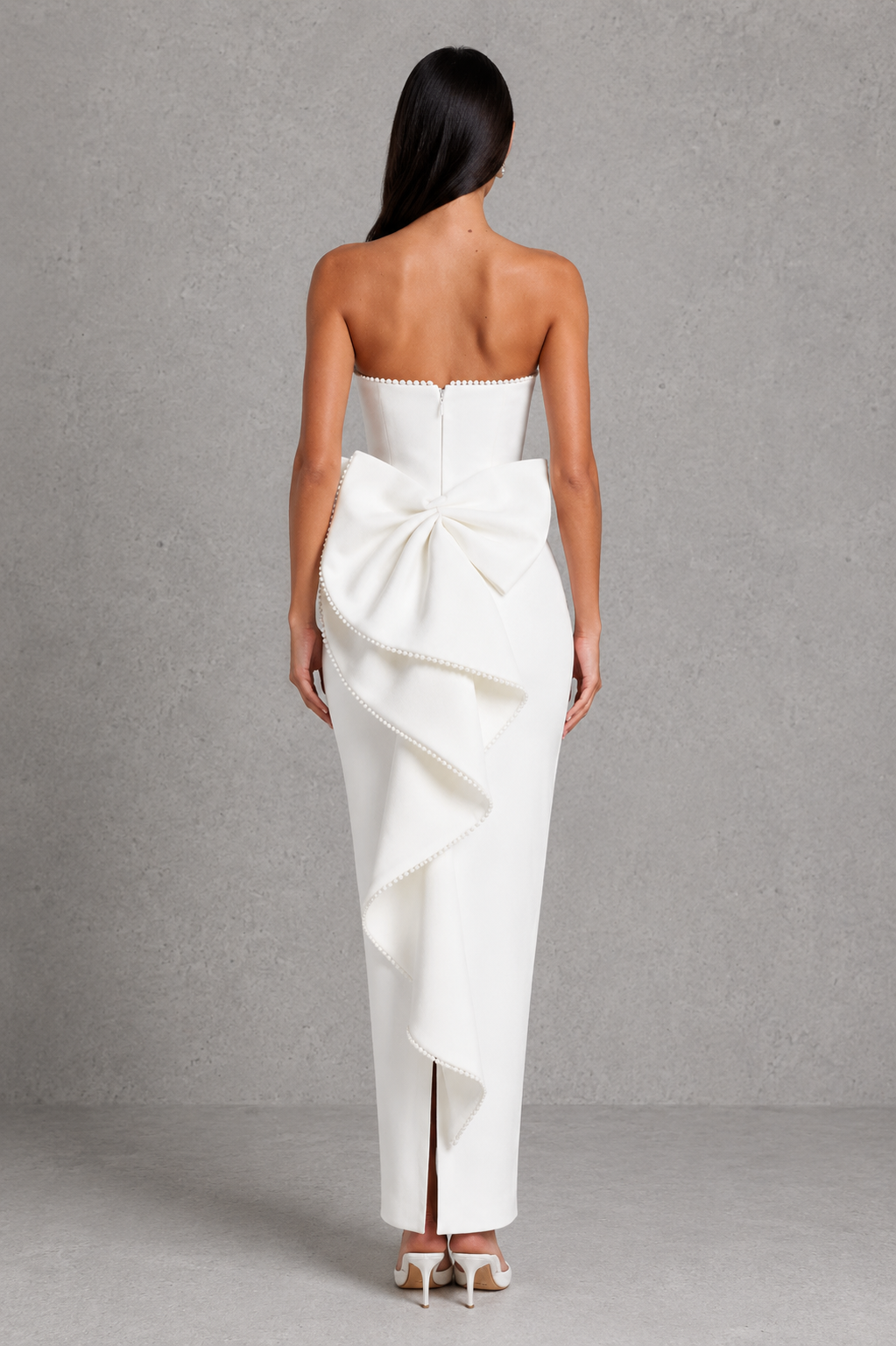 Women's strapless maxi dress in structured crepe featuring a pearl-trimmed neckline, fitted bodice, defined waist, sleek column skirt, centre back split, and detachable oversized bow for elegant evening and formal occasions.