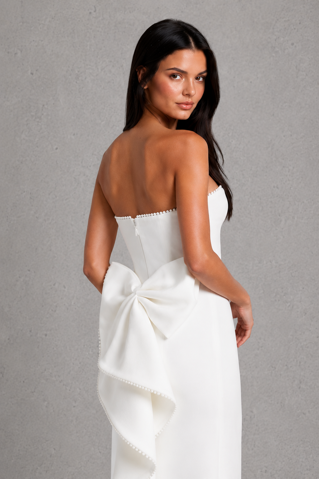 Women's strapless maxi dress in structured crepe featuring a pearl-trimmed neckline, fitted bodice, defined waist, sleek column skirt, centre back split, and detachable oversized bow for elegant evening and formal occasions.