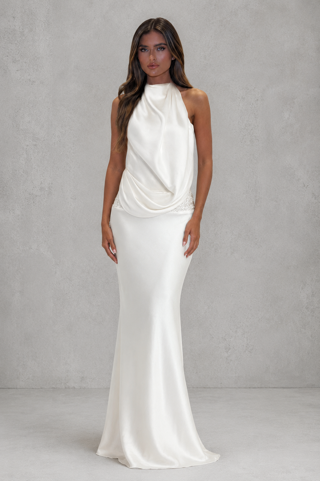 Women’s textured satin maxi dress with draped asymmetric cowl detail, embellished waistband, dropped waist, and lightly flared skirt.