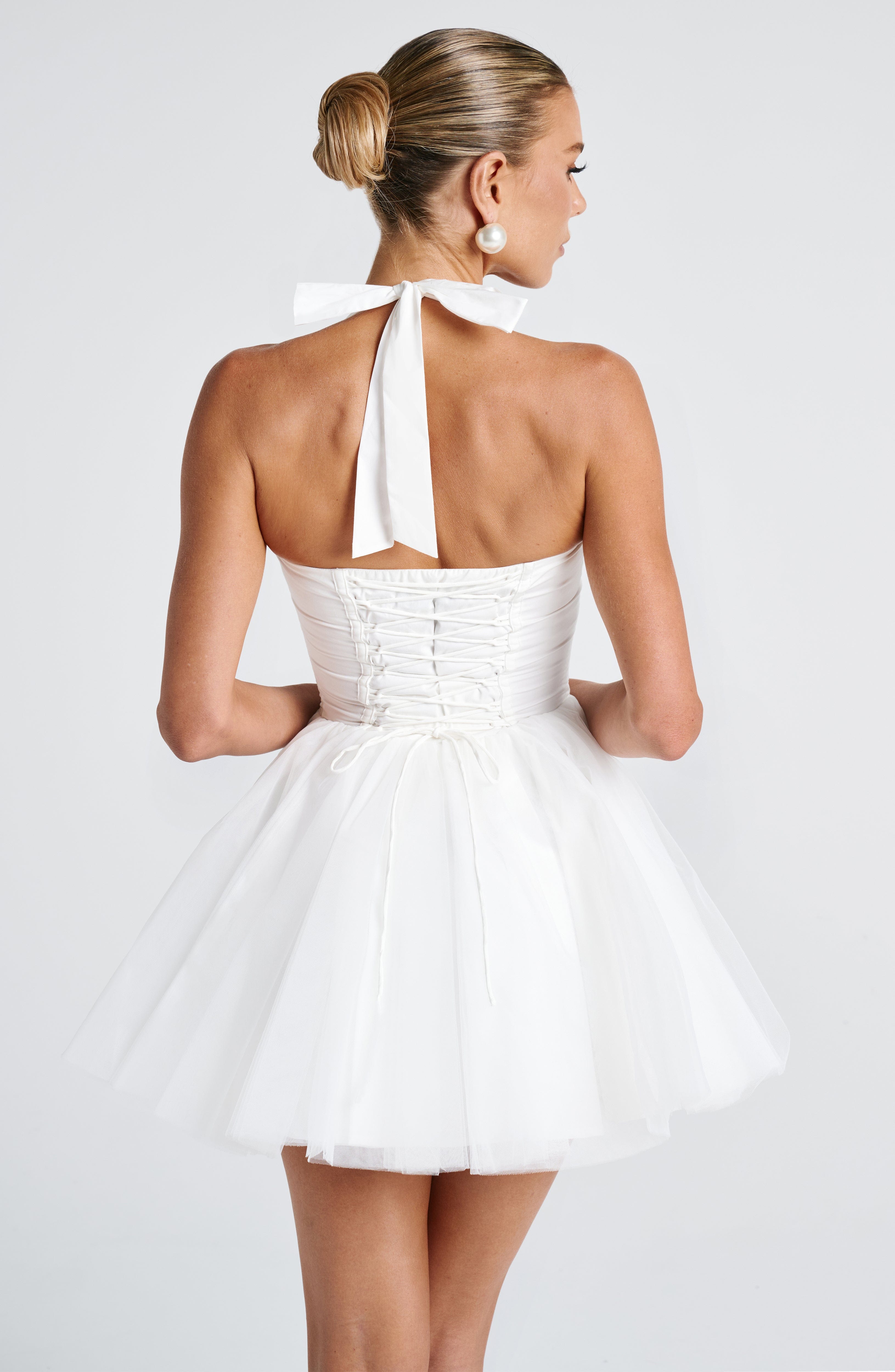 Women’s corset mini dress with sweetheart neckline, halter neck, lace-up back, fitted bodice, and voluminous tulle skirt.