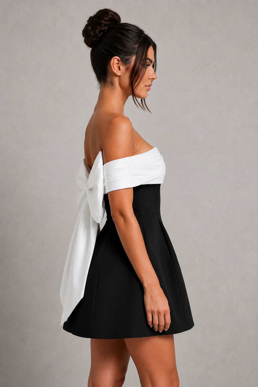 Woman wearing a Bardot off-the-shoulder mini dress with a fitted crepe bodice, contrast neckline, voluminous bubble skirt, and statement bow detail at the back for parties and special occasions.
