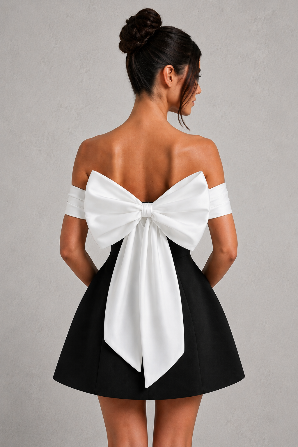 Woman wearing a Bardot off-the-shoulder mini dress with a fitted crepe bodice, contrast neckline, voluminous bubble skirt, and statement bow detail at the back for parties and special occasions.