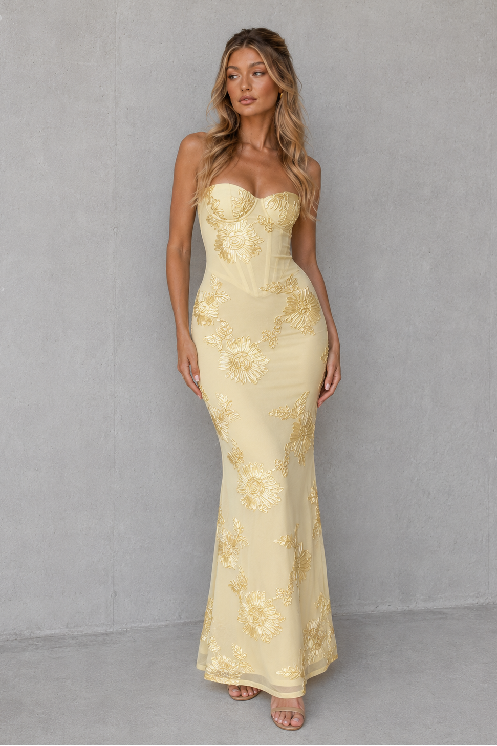 Woman wearing a women's floral embroidered corset maxi dress with a fitted bodice, delicate shoulder straps, defined waist, and flowing full-length skirt, designed for weddings, formal events, and special occasions.