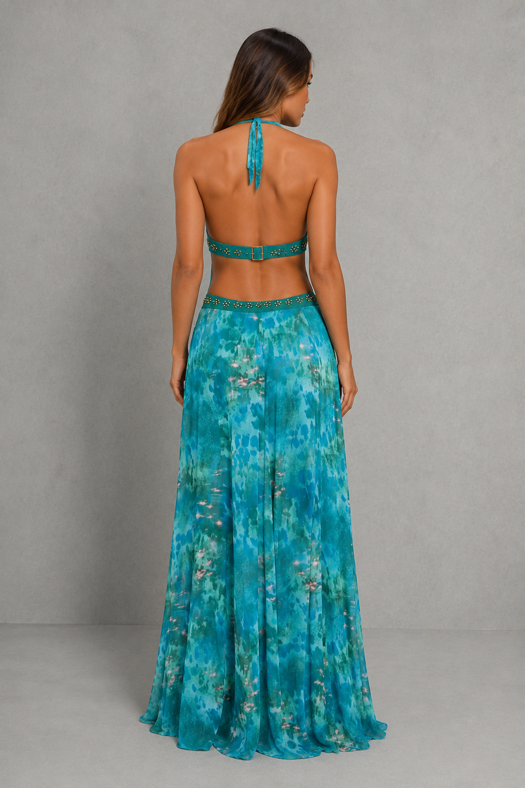 Women’s halter backless maxi dress with plunging neckline, beaded waist detailing, fitted silhouette, and flowing waterfall hem.